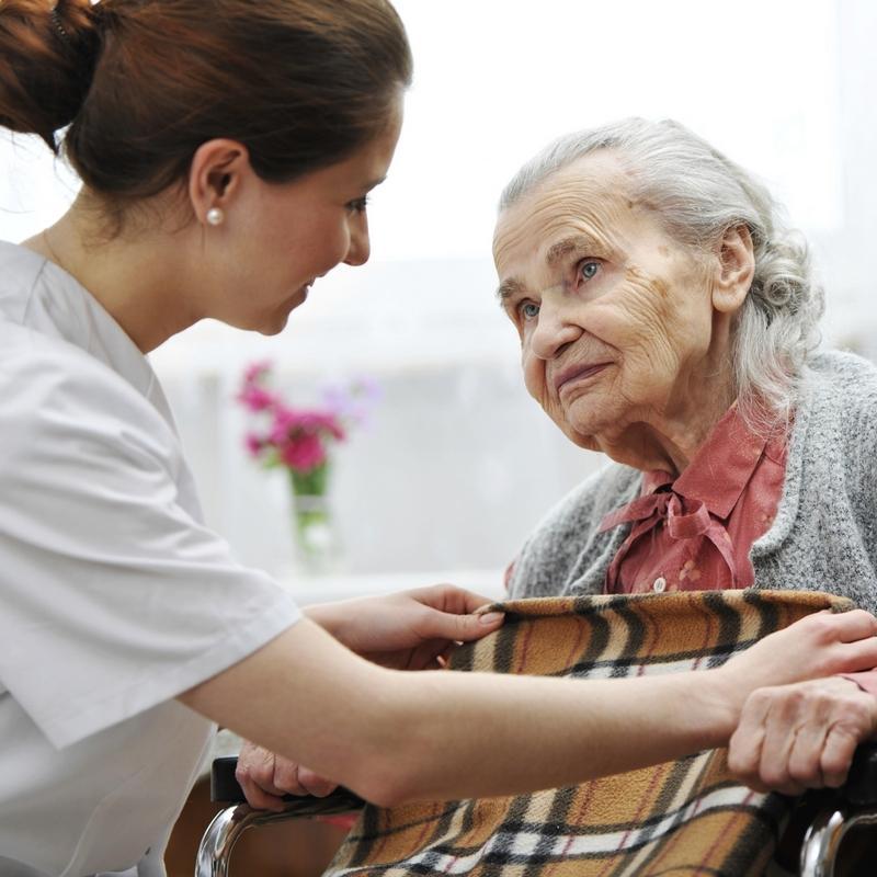 Smiling nurse taking care of old woman